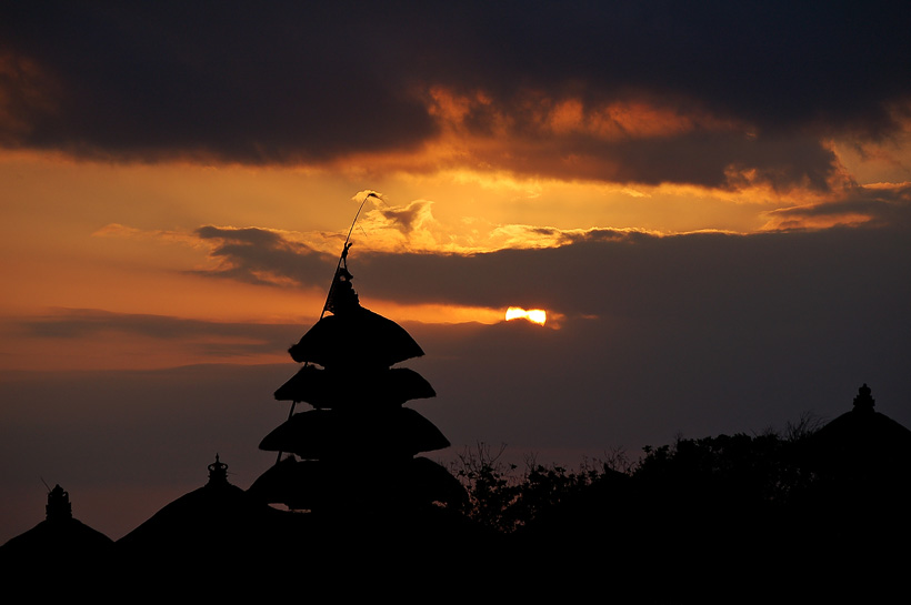 Hindu tempel als silhouet voor een oranjerode zonsondergang bij Uluwatu, Bali.