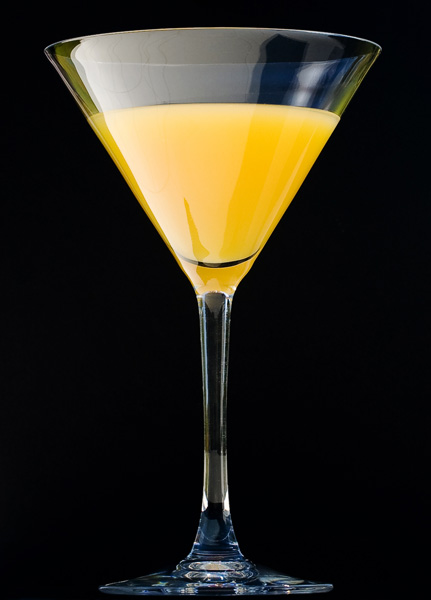 Productfoto van een cocktailglas met - helaas - jus d’orange. Hoewel het een studiobeeld lijkt is de foto in werkelijkheid gemaakt op een tuintafel met twee zwarte A4’tjes en een stukje folie als diffuser voor het harde zonlicht.