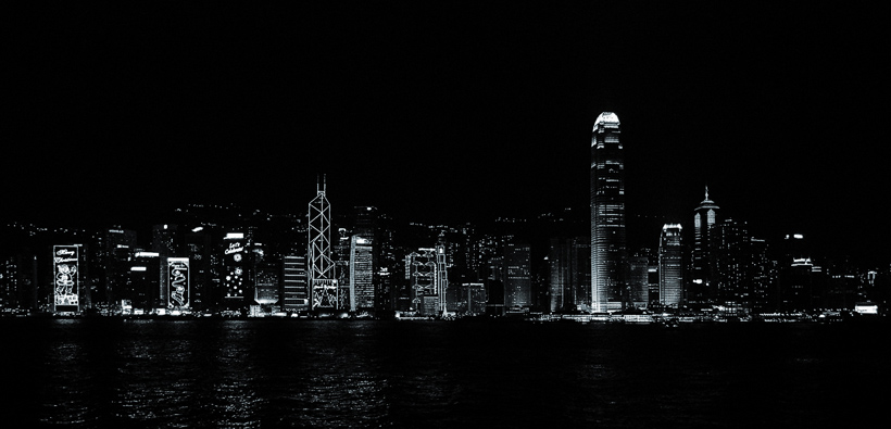 Skyline van Hong Kong’s Central District gezien vanaf Tsim Sha Tsui waterfront. Omdat de foto zonder statief is gemaakt koos ik voor een korte sluitertijd zodat alleen de lampen van de gebouwen zichtbaar zijn en een zwart-wit effect geven. Bijkomend voordeel is dat er nog ’leven’ in het water zit.